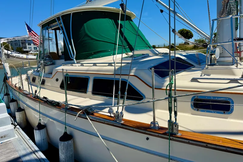 Slide: The Image of 2003 Island Packet 485 sailboat docked, featuring green canopy and American flag. - 15