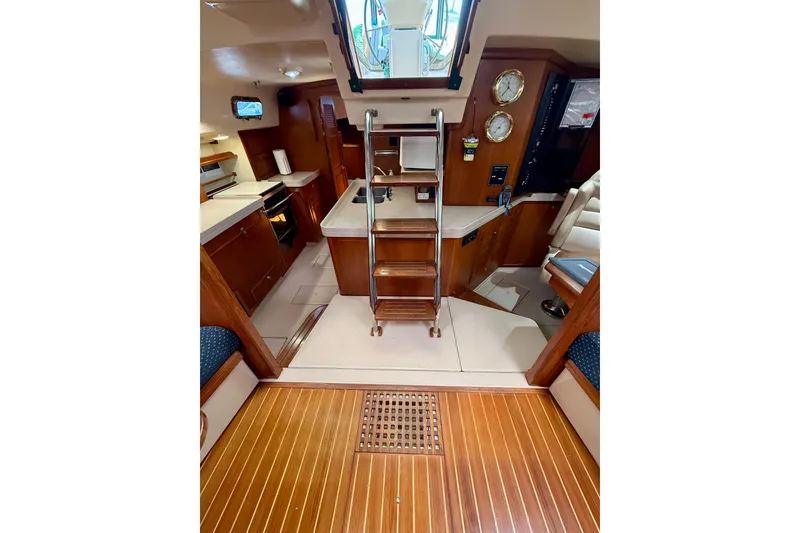 Slide: The Image of Interior of 2006 Island Packet 485 yacht, featuring a wooden floor, kitchen, and seating area. - 24