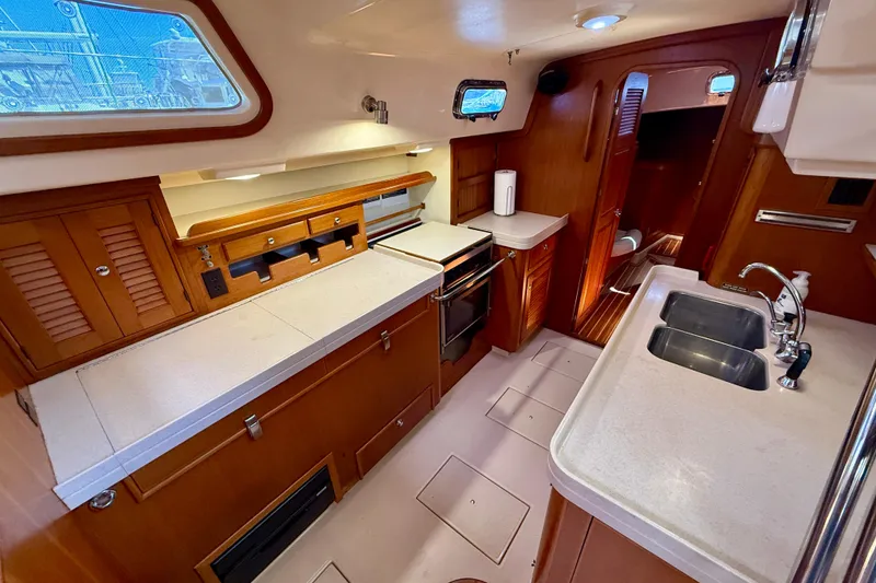 Slide: The Image of Interior of 2006 Island Packet 485 yacht, featuring a well-equipped galley with wooden cabinetry. - 26