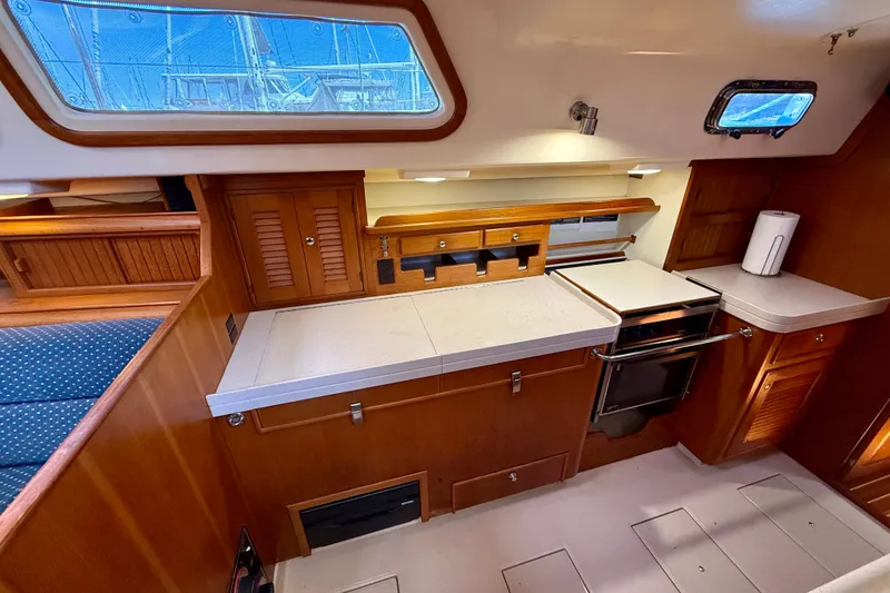 Slide: The Image of 2006 Island Packet 485 yacht interior kitchen with wooden cabinetry and modern appliances. - 27