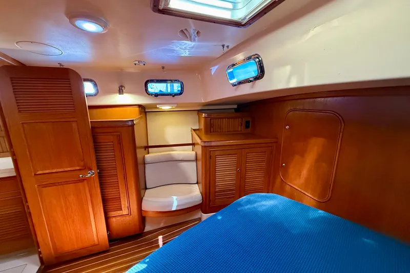 Slide: The Image of Cozy cabin interior of 2006 Island Packet 485 yacht with wooden furnishings and blue bedding. - 36