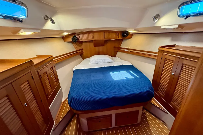 Slide: The Image of Cozy cabin interior of 2006 Island Packet 485 yacht with wooden furnishings and blue bedding. - 39