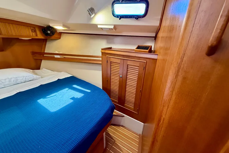Slide: The Image of Cozy cabin interior of 2006 Island Packet 485 yacht with wooden finishes and blue bedding. - 41