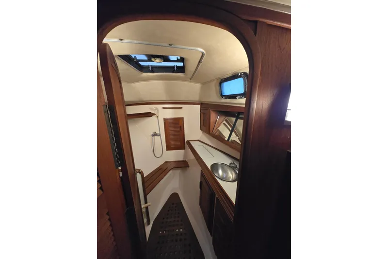 Slide: The Image of Interior of 1979 Islander Freeport 36 sailboat, featuring a compact bathroom with wooden accents. - 23