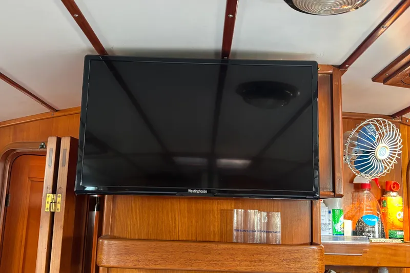 Slide: The Image of Flat-screen TV on 1988 Tayana 52 yacht interior with wooden paneling and fan. - 56