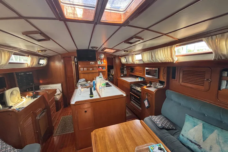 Slide: The Image of Interior of 1988 Tayana 52 yacht, featuring cozy wood paneling and a well-equipped kitchen area. - 64