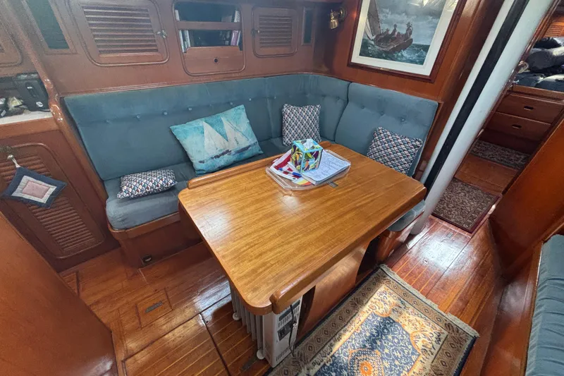 Slide: The Image of Cozy interior of 1988 Tayana 52 yacht with wooden table and cushioned seating. - 57