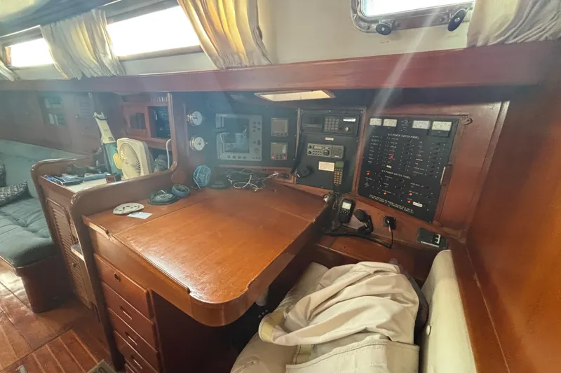 Slide: The Image of Navigation station inside 1988 Tayana 52 yacht, featuring control panels and wooden cabinetry. - 48
