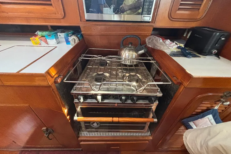 Slide: The Image of Galley kitchen in 1988 Tayana 52 yacht with stove, kettle, and wooden cabinetry. - 53