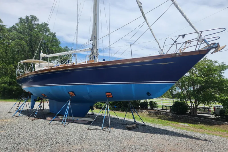 Slide: The Image of 1988 Tayana 52 sailboat on stands, blue hull, outdoors on gravel. - 2