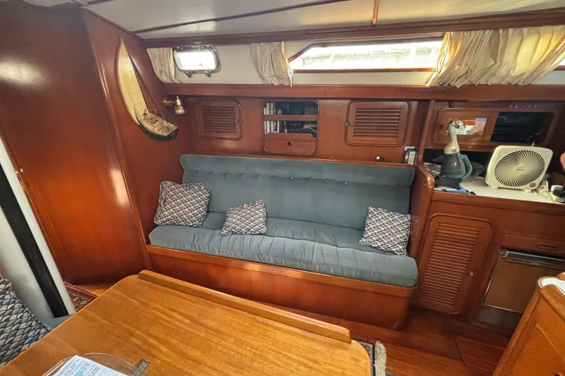 Slide: The Image of Interior of 1988 Tayana 52 yacht with wooden cabinetry and blue cushioned seating. - 58