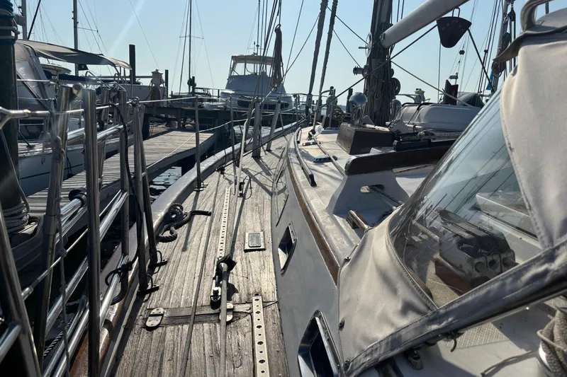 Slide: The Image of 1988 Tayana 52 sailboat docked at marina, showcasing wooden deck and rigging. - 35