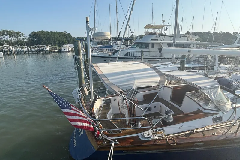 Slide: The Image of 1988 Tayana 52 sailboat docked at marina with American flag. - 24