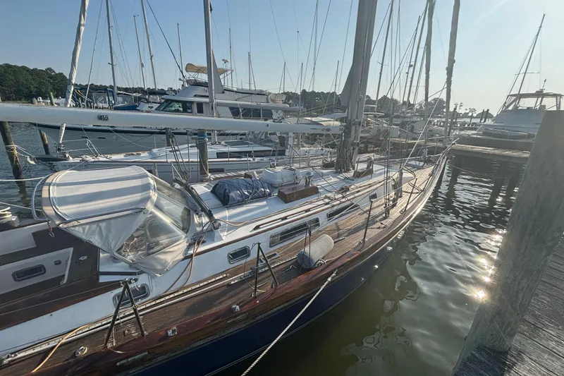 Slide: The Image of 1988 Tayana 52 sailboat docked at marina, surrounded by other boats. - 25
