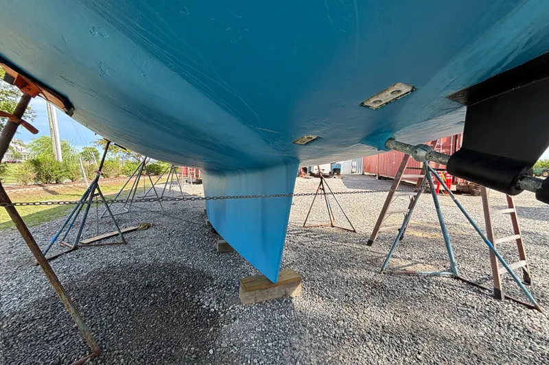 Slide: The Image of Bottom view of a 1988 Tayana 52 sailboat on stands, showcasing its blue hull. - 21