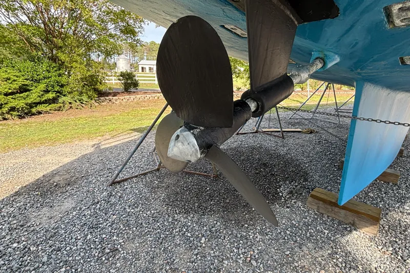 Slide: The Image of Propeller of 1988 Tayana 52 sailboat on dry dock, surrounded by greenery. - 19