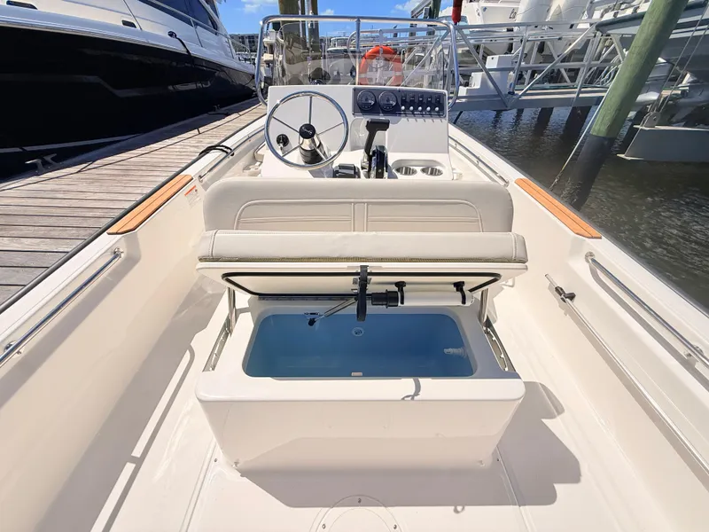 Slide: The Image of The image shows the cockpit of a 2027 Boston Whaler 190 Montauk. It features a steering wheel, instruments, and a bench seat with storage underneath. - 26