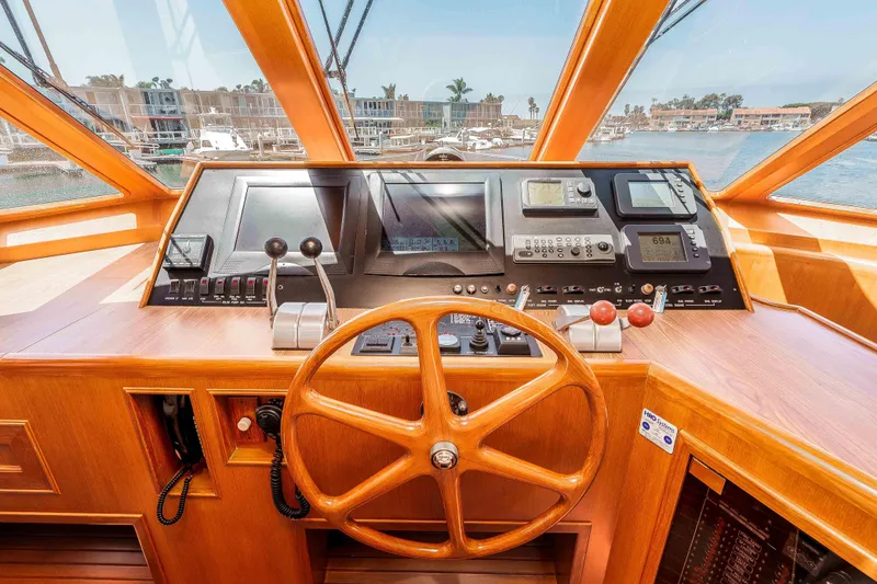 Slide: The Image of Pilothouse interior of 2005 Offshore Yachts 54, featuring wooden steering wheel and navigation controls. - 32