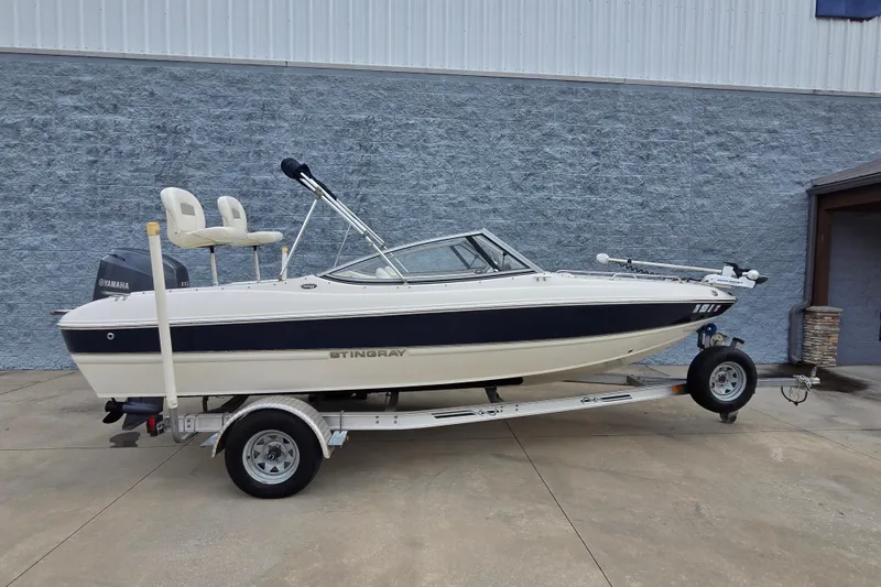 The Image of 2013 Stingray 191 LX boat on trailer, featuring Yamaha outboard motor, parked outdoors. - 1