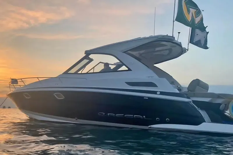 The Image of 2015 Regal 35 Sport Coupe yacht on water at sunset with flags. - 1