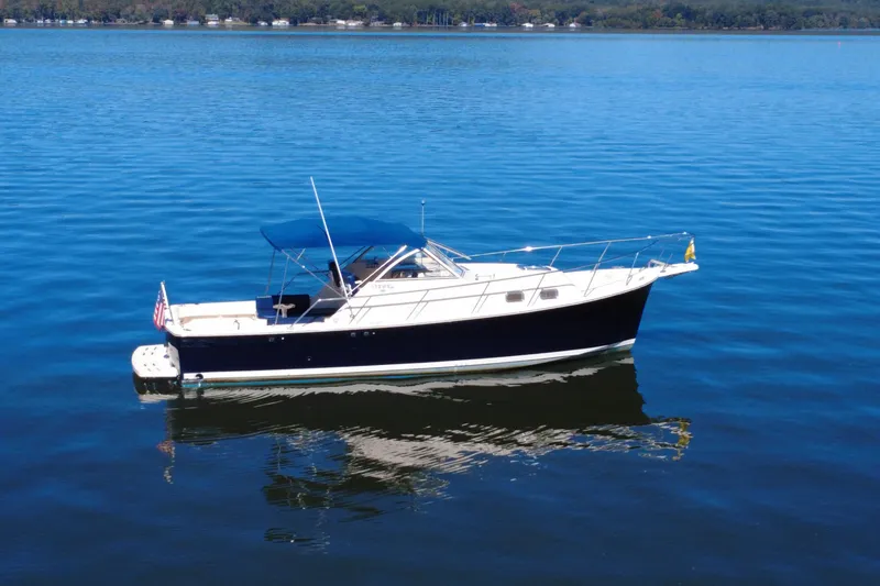 Slide: The Image of 2003 Mainship Pilot 30-II boat on calm blue water with canopy. - 1