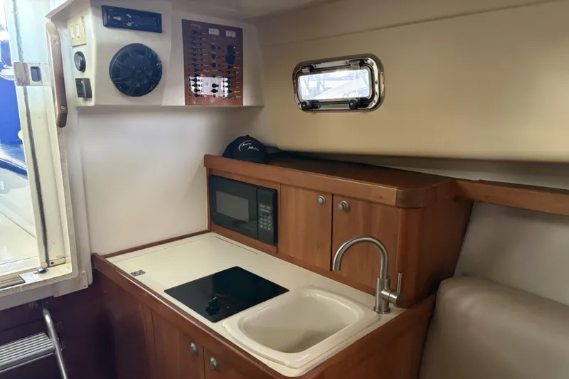 Slide: The Image of 2003 Mainship Pilot 30-II interior with kitchenette, sink, and microwave. - 11