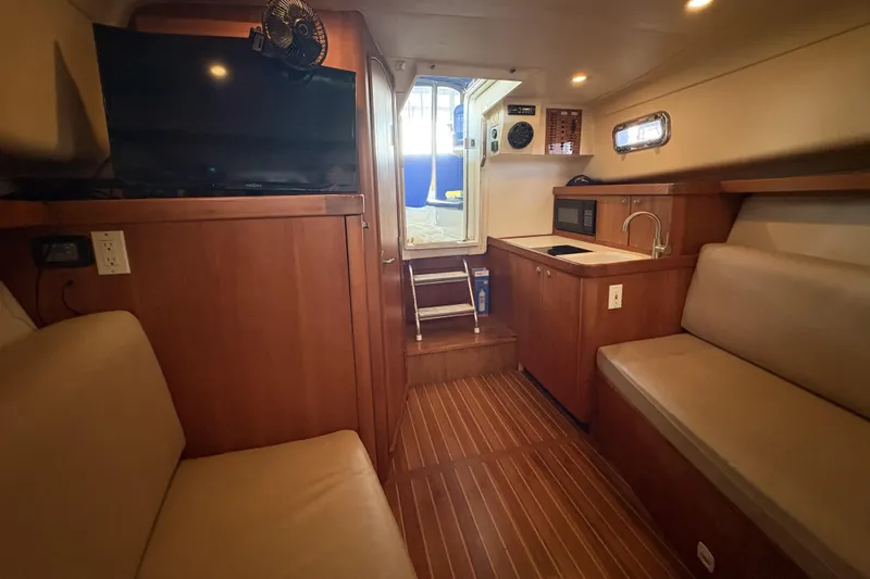 Slide: The Image of 2003 Mainship Pilot 30-II interior with wood finish, kitchenette, and seating area. - 13