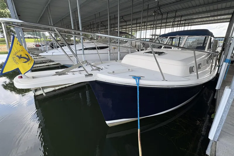 Slide: The Image of 2003 Mainship Pilot 30-II docked under a covered marina, featuring a sleek navy hull. - 5