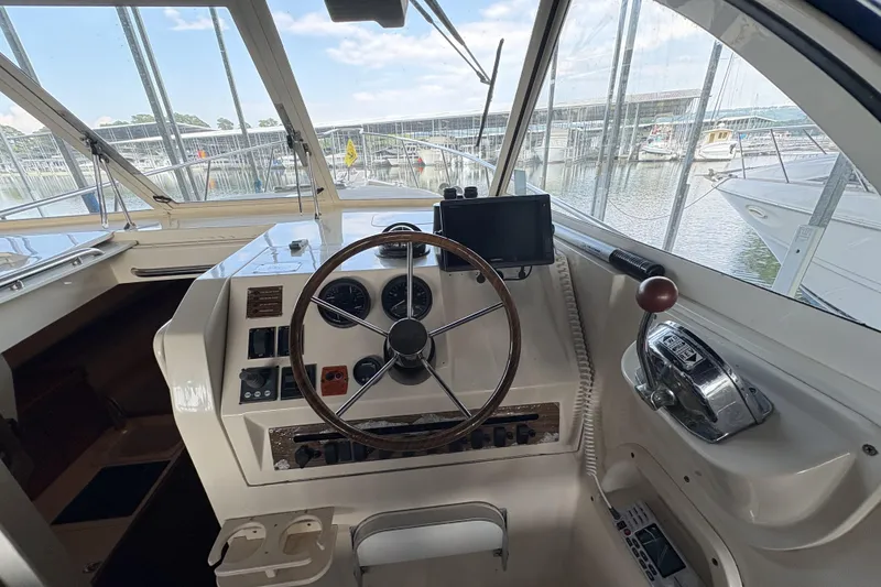 Slide: The Image of 2003 Mainship Pilot 30-II helm with steering wheel, controls, and marina view. - 9
