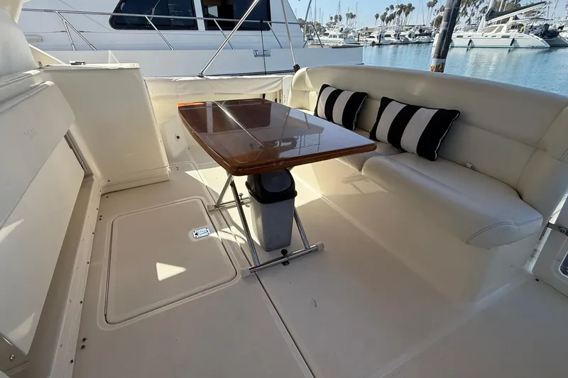 Slide: The Image of 1998 Tiara Yachts 3500 Express interior with seating and table, docked at marina. - 14