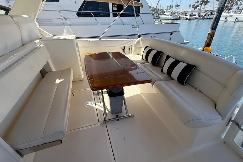 Slide: The Image of 1998 Tiara Yachts 3500 Express interior with white seating, wooden table, and striped cushions. - 15