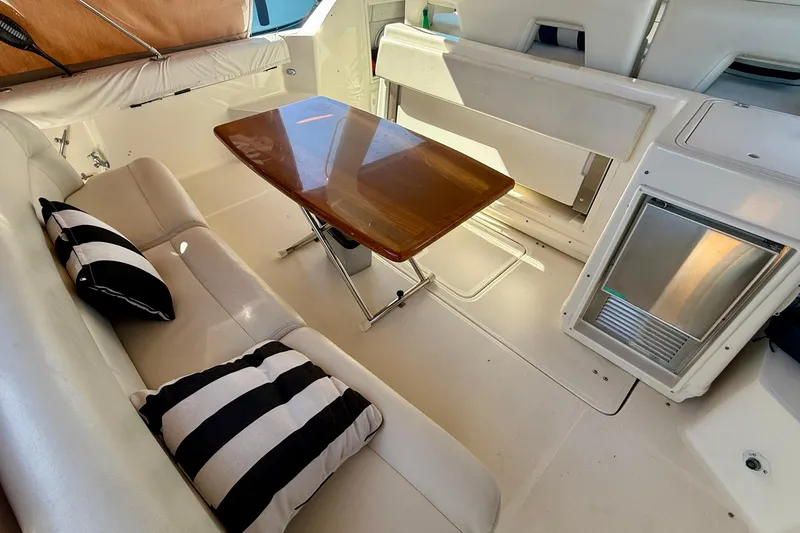Slide: The Image of 1998 Tiara Yachts 3500 Express interior with seating, table, and striped cushions. - 16