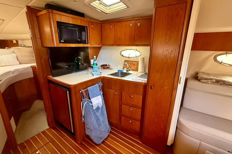 Slide: The Image of 1998 Tiara Yachts 3500 Express interior with kitchenette, featuring wood cabinetry and modern amenities. - 26