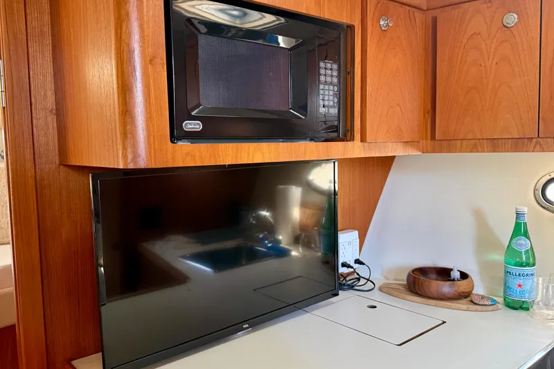 Slide: The Image of 1998 Tiara Yachts 3500 Express interior with microwave, TV, and wooden cabinetry. - 27