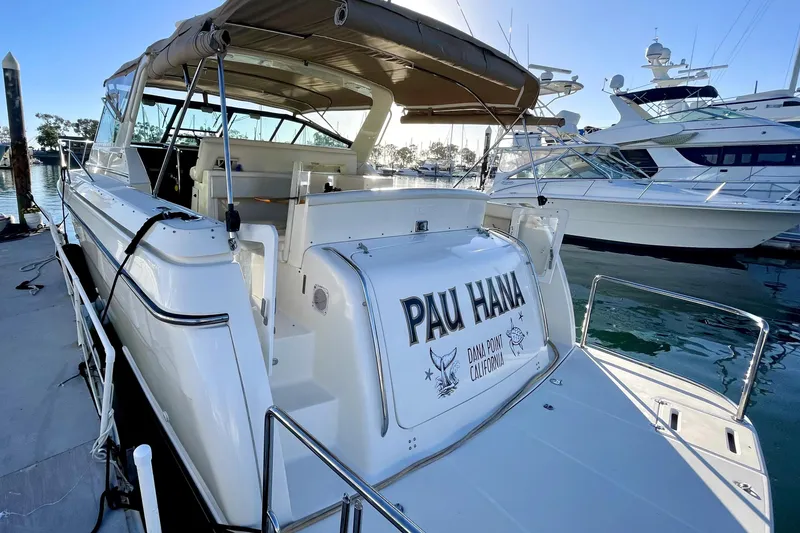 Slide: The Image of 1998 Tiara Yachts 3500 Express docked, featuring "Pau Hana" nameplate, sunny marina setting. - 3