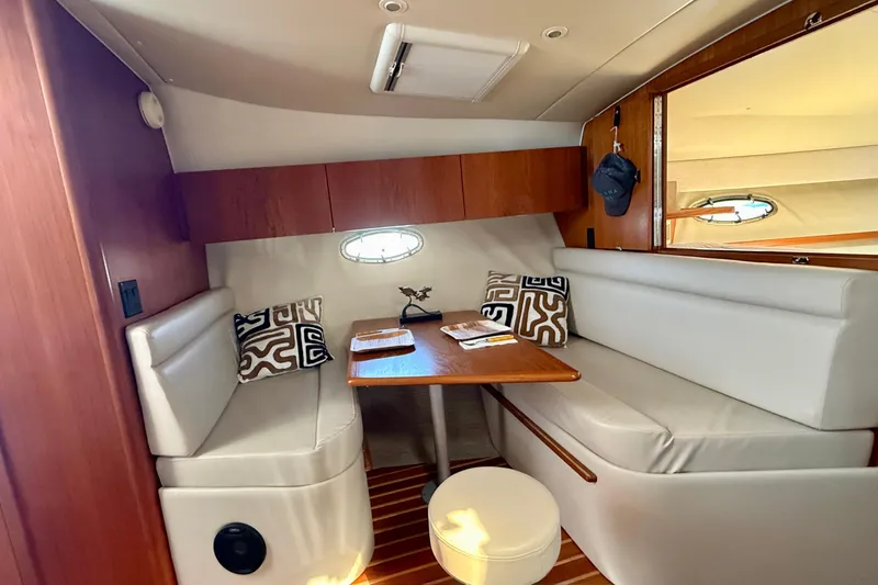 Slide: The Image of 1998 Tiara Yachts 3500 Express cabin with cozy seating and wooden table. - 32