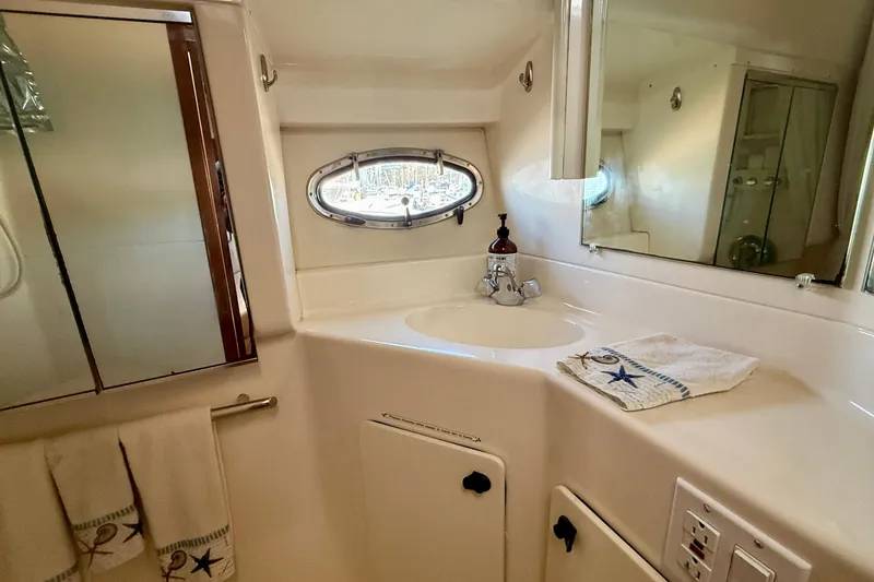 Slide: The Image of Bathroom interior of 1998 Tiara Yachts 3500 Express with sink, mirror, and nautical-themed towels. - 33