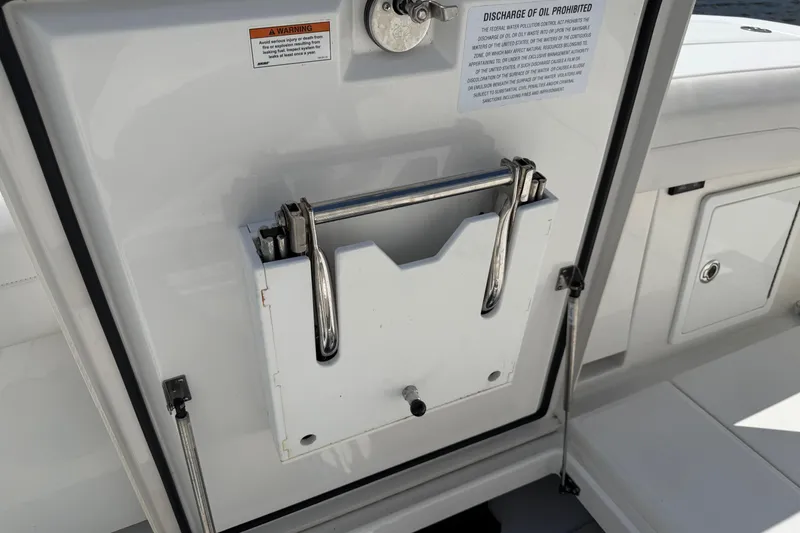 Slide: The Image of 2023 Regulator 37 boat storage compartment with safety and oil discharge warnings. - 15