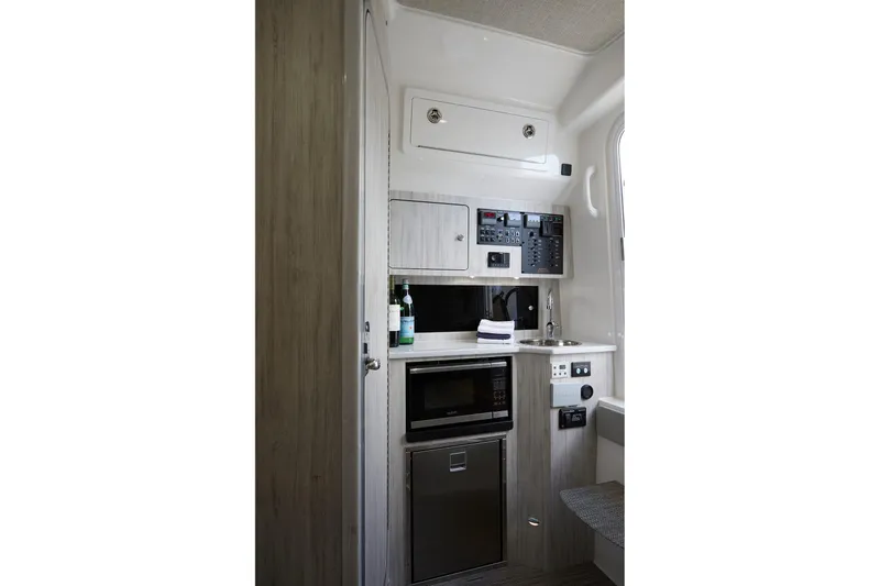 Slide: The Image of Interior of 2023 Regulator 37 boat featuring a compact kitchenette with modern appliances. - 30