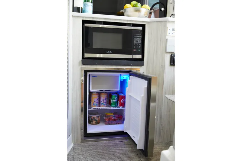 Slide: The Image of 2023 Regulator 37 boat kitchen with microwave and open mini fridge stocked with drinks. - 31
