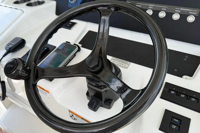 Slide: The Image of Carbon fiber steering wheel on 2023 Regulator 37 boat dashboard with controls and smartphone. - 8