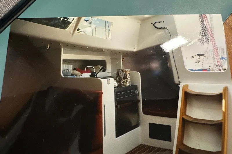 Slide: The Image of Interior of a 1999 Bravura B35 sailboat, featuring a compact kitchen and wooden steps. - 14