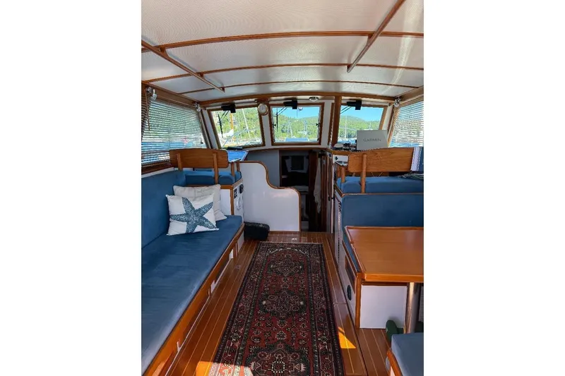 Slide: The Image of Interior of a 1995 Wilbur Weekender boat with cozy seating and nautical decor. - 13
