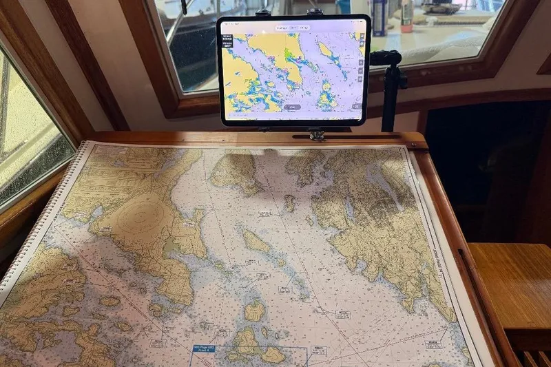 Slide: The Image of Navigational charts and tablet on 1995 Wilbur Weekender boat, showcasing maritime route planning. - 16