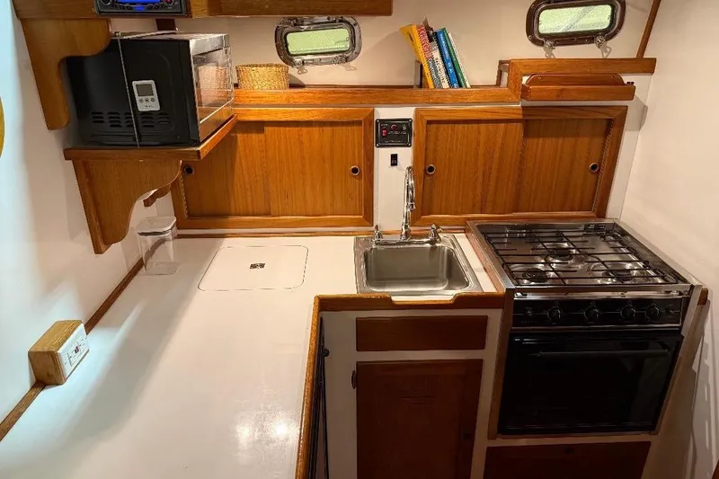 Slide: The Image of 1995 Wilbur Flybridge Cruiser kitchen with stove, sink, microwave, and wooden cabinetry. - 20