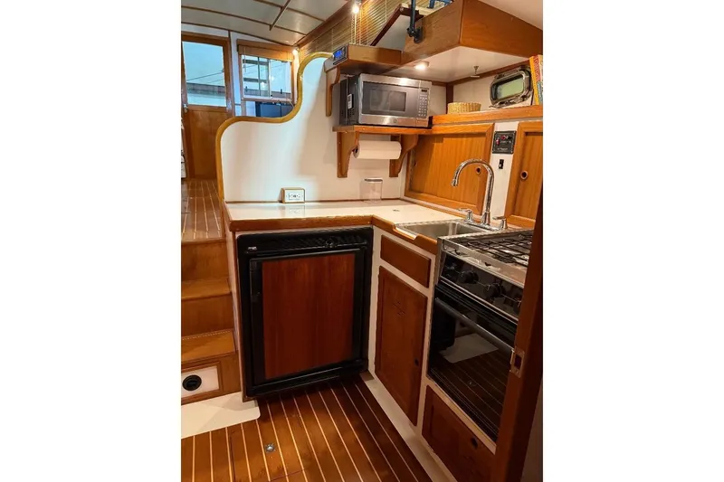 Slide: The Image of Interior of 1995 Wilbur Flybridge Cruiser with kitchenette, featuring wood cabinetry and modern appliances. - 21