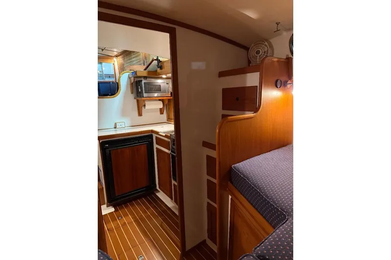 Slide: The Image of Interior of a 1995 Wilbur Weekender boat featuring a compact kitchen and cozy sleeping area. - 29