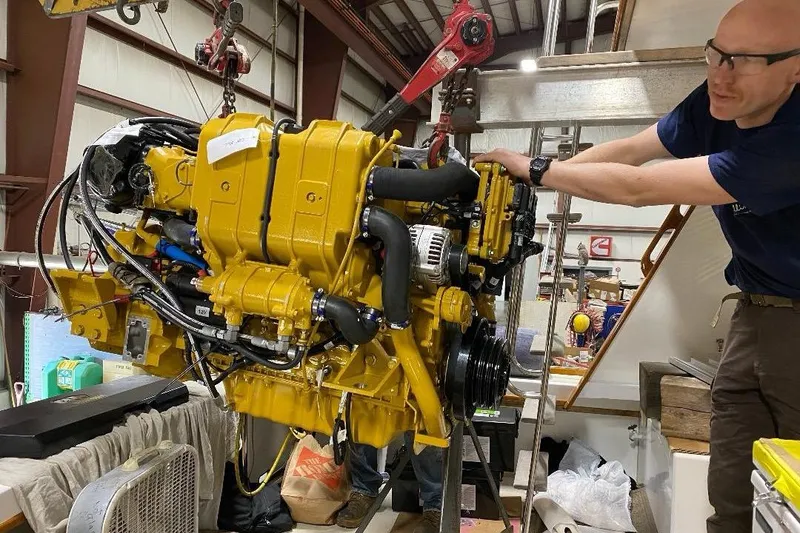 Slide: The Image of Man installing engine in 1995 Wilbur Weekender boat, using hoist in workshop. - 31
