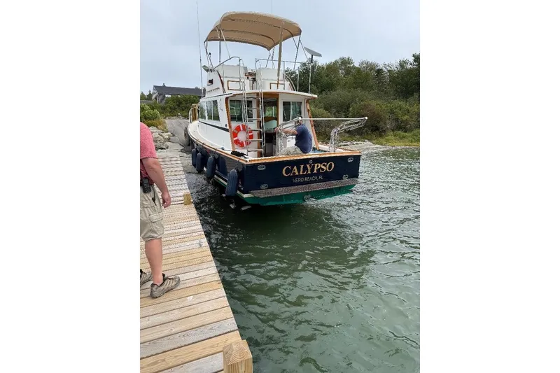 Slide: The Image of A 1995 Wilbur Weekender boat named "Calypso" docked at a wooden pier. - 37
