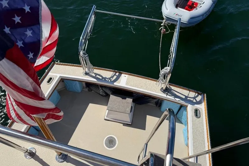 Slide: The Image of 1995 Wilbur Weekender boat deck with American flag and inflatable dinghy on water. - 6